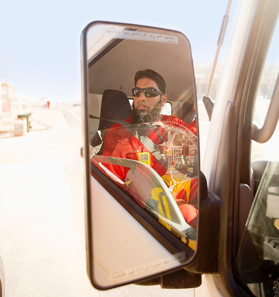 A vehicle mirror shows a man driving the vehicle