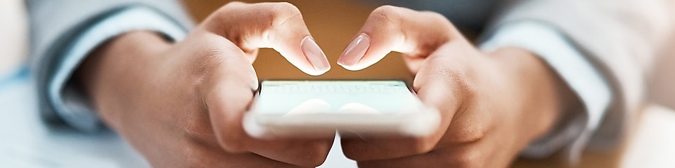 Two hands shown using a blackberry device to send an email