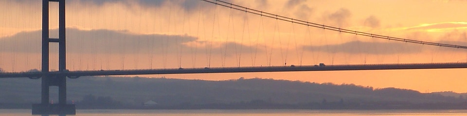 a suspension bridge over a river at sunset
