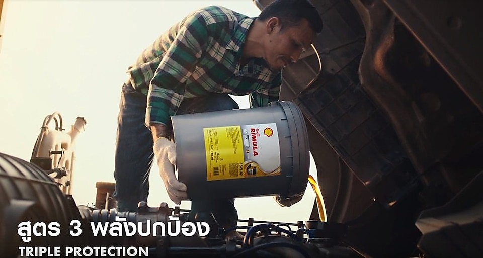 Man filling rimula oil in engine