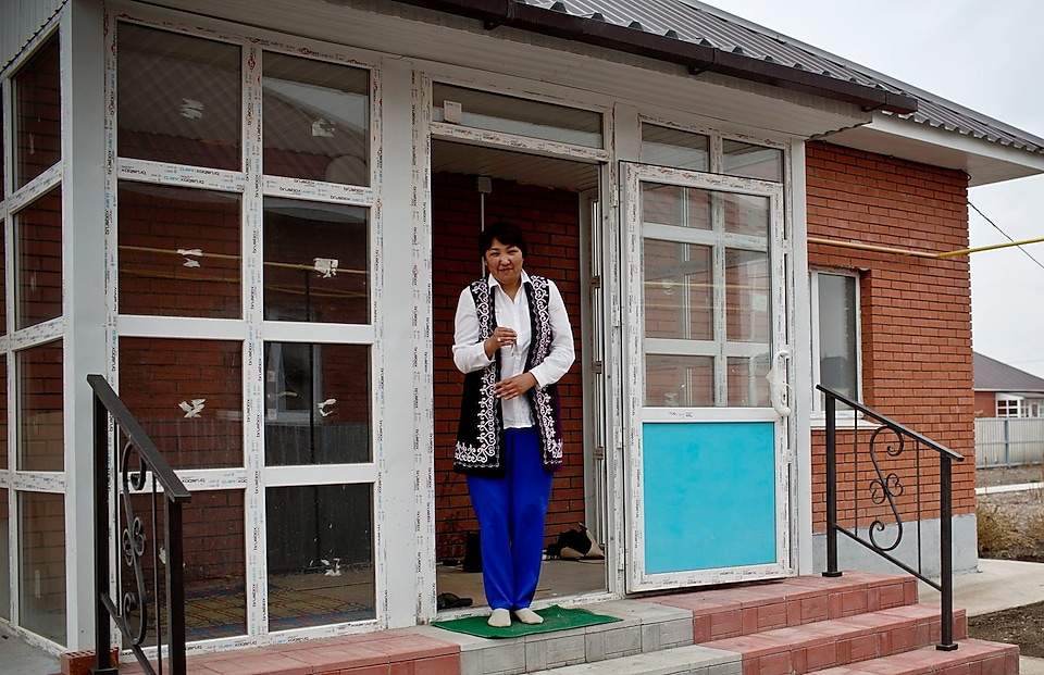 A lady standing outside her new house after relocating in Kazakhstan