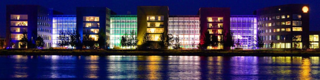 เงาของอาคารสำนักงานที่เปิดไฟสว่างในเวลากลางคืนสะท้อนบนผิวน้ำ