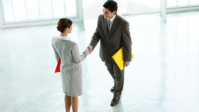 นักธุรกิจหญิงและชายจับมือกันที่ล็อบบี้