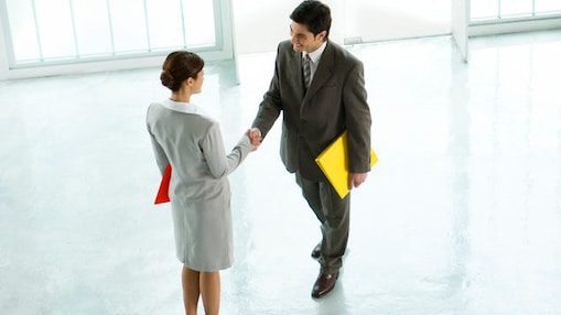 นักธุรกิจหญิงและชายจับมือกันที่ล็อบบี้