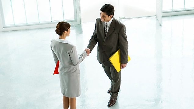 นักธุรกิจหญิงและชายจับมือกันที่ล็อบบี้