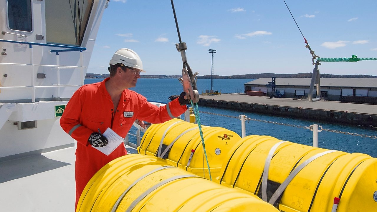 พนักงานกำลังตรวจสอบอุปกรณ์บนเรือที่จอดเทียบท่า