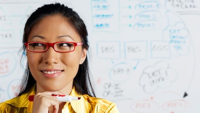 Close up of Asian businesswoman smiling in front of whiteboard