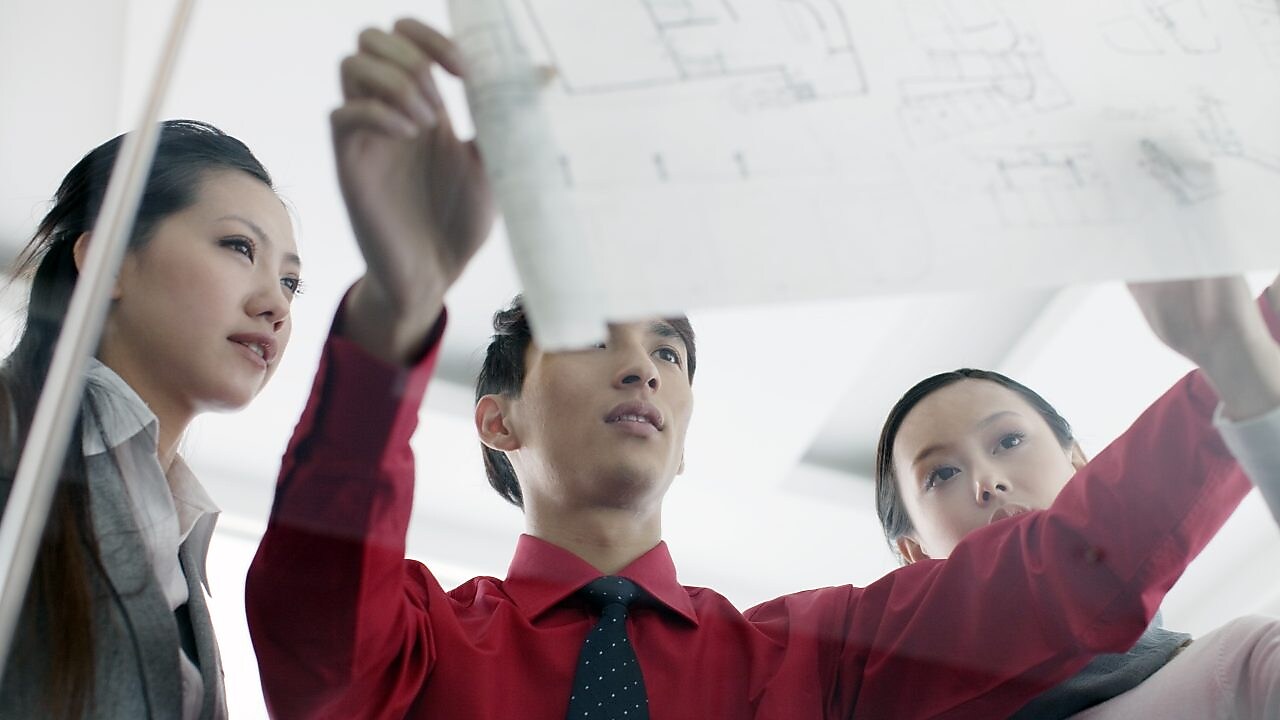 ผู้ชายแสดงพิมพ์เขียวให้เพื่อนร่วมงานดู