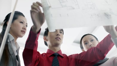 ผู้ชายแสดงพิมพ์เขียวให้เพื่อนร่วมงานดู