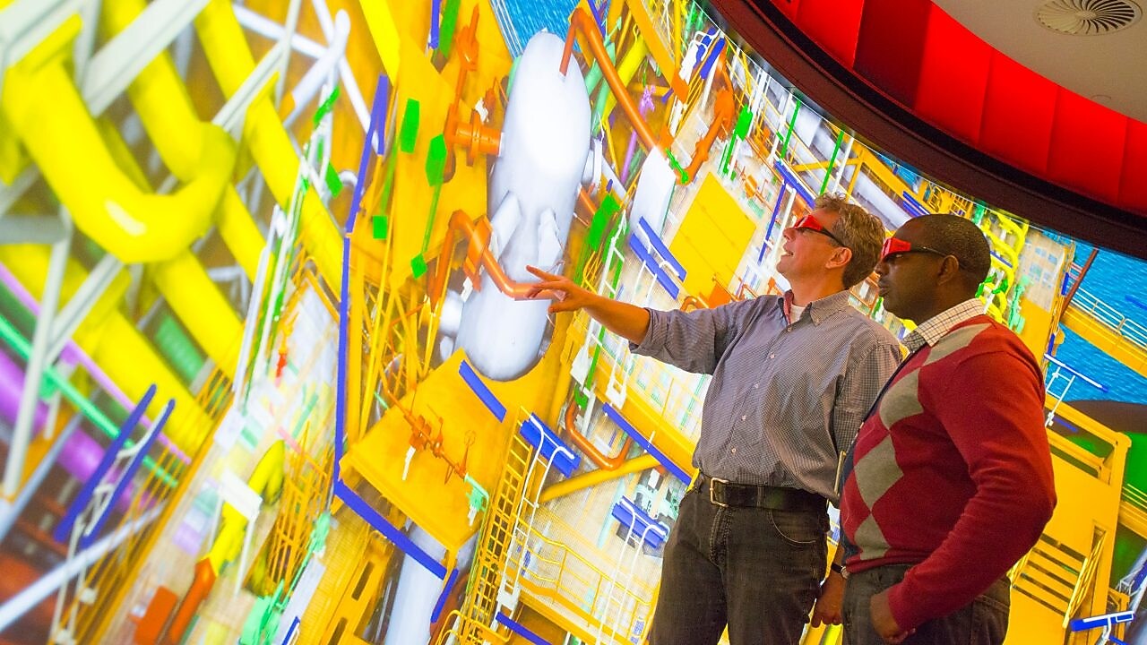 ผู้ชายสองคนกำลังดูหน้าจอขนาดใหญ่ด้วยแว่น 3 มิติ