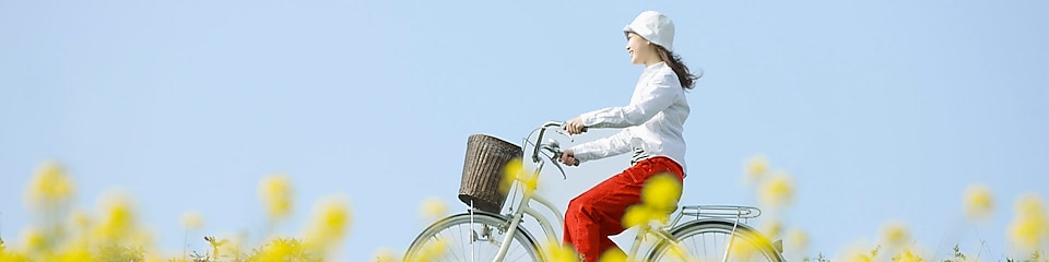 หญิงสาวขี่จักรยานผ่านทุ่งหญ้าในฤดูร้อน