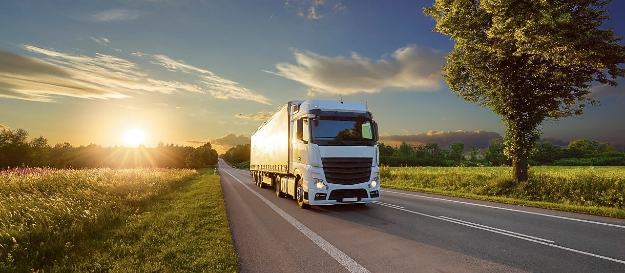 a truck is driving on a flat road in countryside