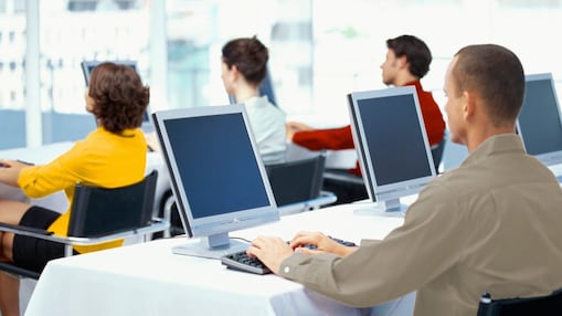 มุมมองด้านหลังของสี่นักธุรกิจที่ใช้คอมพิวเตอร์ในสำนักงาน