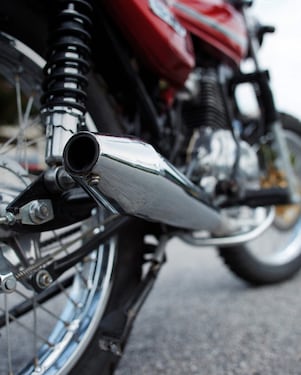 รถจักรยานยนต์จอดอยู่บนถนนที่กล้องกำลังจับภาพไปที่ท่อไอเสีย และล้อ